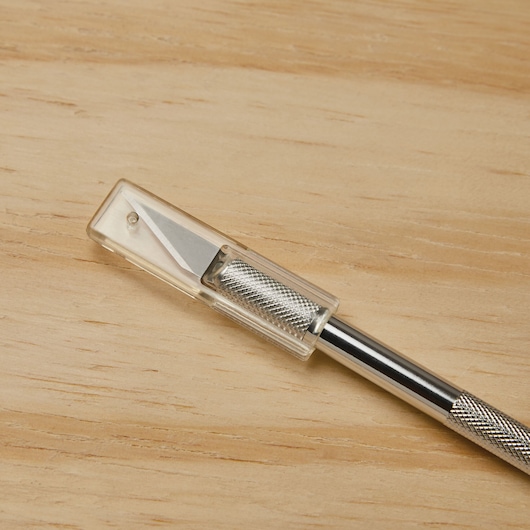 STANLEY 10-401 precision hobby knife with silver textured handle and clear safety cap, photography on wood surface.