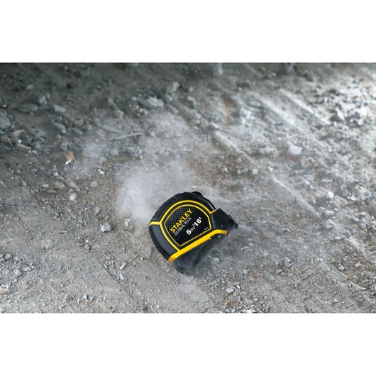 STANLEY 30-615 tape measure, black and yellow, on rough concrete surface, product photography.
