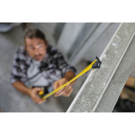 STANLEY 30-626 tape measure in use, yellow tape extended along a metal beam, side angle photography.