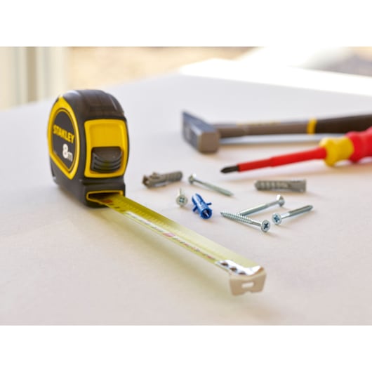 STANLEY 30-757 tape measure photography, yellow and black, with screws and tools on white surface