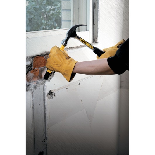 Stanley 51-082 hammer with yellow handle used for demolition near a window by gloved hands.