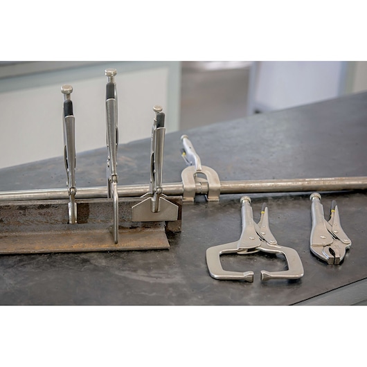 Photo of STANLEY 84-399 locking pliers and clamps on a metal workbench, showcasing various types in use.