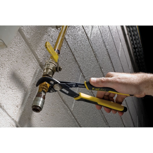 STANLEY 84-648 adjustable pliers used on a pipe, close-up with yellow and black handles.