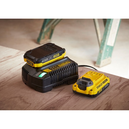 STANLEY SC200 battery charger and battery pack, yellow and black, angled view on wooden surface.