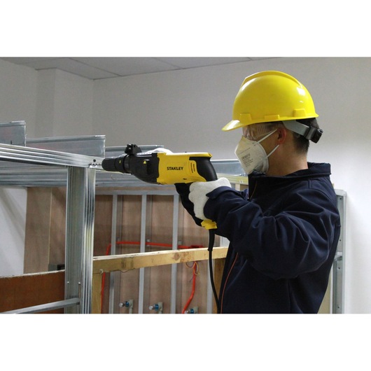 STANLEY SHR264 yellow corded screwdriver in use on metal frame, worker with hard hat and gloves.