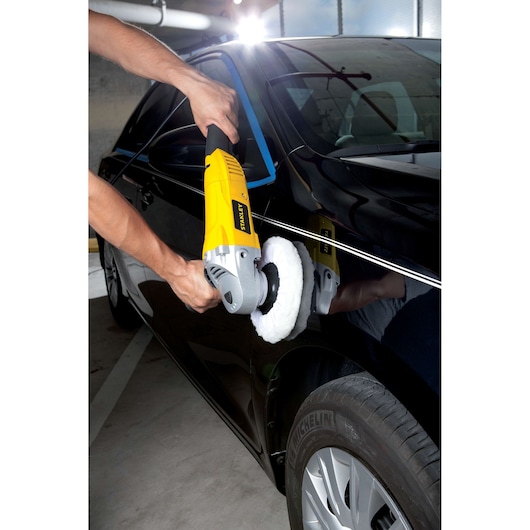 STANLEY STGP1318K polisher being used on a black car’s door in a parking garage.