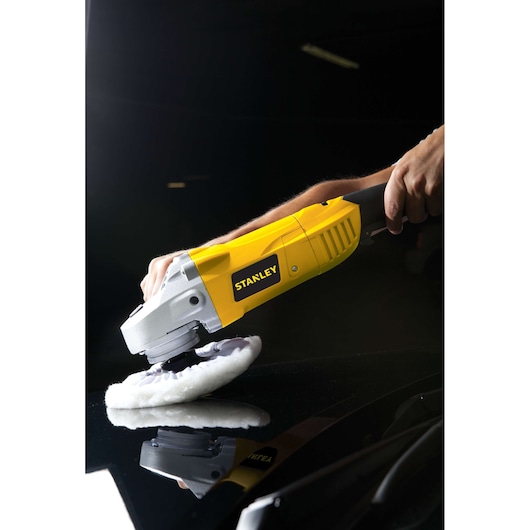 Photo of STANLEY STGP1318K polisher in use, yellow body, polishing a black surface.