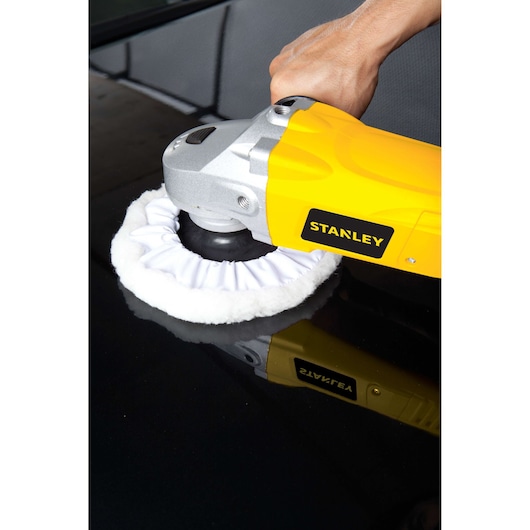Photo of STANLEY STGP1318K polisher in use, yellow and silver body, polishing a black surface.