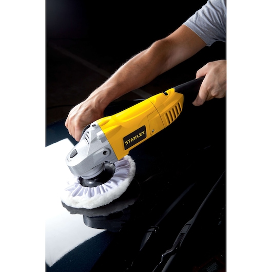 Photo of STANLEY STGP1318K polisher in use on black car surface, yellow body, side angle.