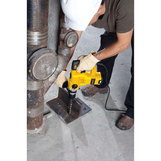 STANLEY STHR1232K hammer drill in use drilling metal base plate, worker in gloves and hard hat.