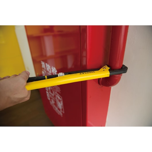Photo of STANLEY STMT75926-8 pipe wrench being used on a red pipe near a red cabinet.