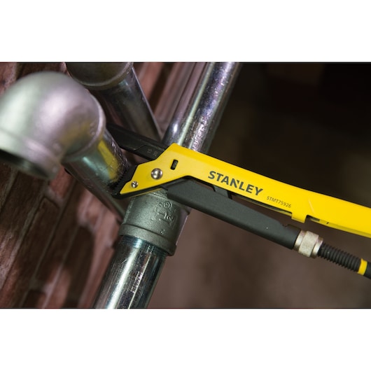 Photo of STANLEY STMT75926-8 adjustable pliers gripping metal pipe fitting, close-up in workshop.