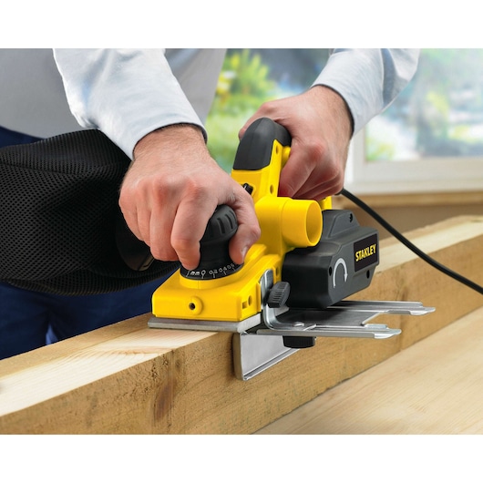 STANLEY STPP7502-B2 electric planer with black handle in use on wood, close-up angle.