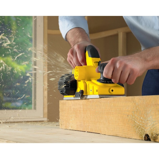 Photo of STANLEY STPP7502-B2 planer used on wood, close-up showing yellow tool in action.