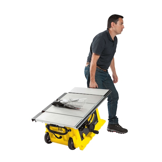 STANLEY STST1825 table saw with yellow base, shown being transported by a person, side angle.
