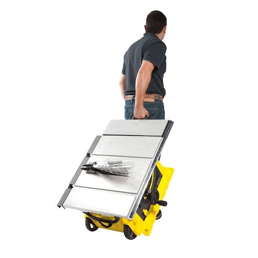 STANLEY STST1825 table saw being wheeled by a person, rear angle, yellow base with silver table surface.