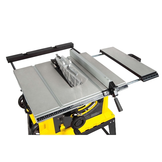 STANLEY STST1825 table saw with metal surface, blade guard, and yellow base, shown from angled top view.